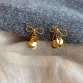 Detalle de pendientes de lazo dorado con lentejuelas sobre fondo de punto - Pendientes de Botón con Borla Dorada