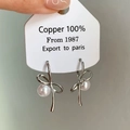 Detalle de pendientes de lazo plateado con perlas blancas en tarjeta de regalo - Pendientes de Botón de Perla con Lazo Plateados