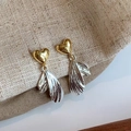 Détail de boucles d'oreilles élégantes cœur et pompon doré sur fond texturé - Boucles d'Oreilles Pendantes Coeur Aile Dorées