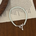 Detailansicht eines Perlenarmbands mit silbernem OT-Verschluss auf Vintage-Leinentuch - 4mm Gletscherblau