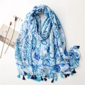 Detail of light blue linen scarf with paisley prints and thick blue tassels on white base - Blue