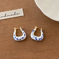 Close-up of handmade U-shaped heart earrings with blue marble enamel and gold finish - U-Shaped Blue And White Porcelain Style