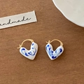 Macro detail of heart-shaped blue and white enamel earrings with golden hooks - Heart-Shaped Blue And White Porcelain Style
