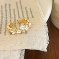 Bague ouverte dorée avec fleurs en émail blanc et zircons sur fond en tissu rustique - Blanc