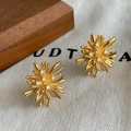 Detail of gold starburst stud earrings featuring zircon inlay on a textured fabric - Gold