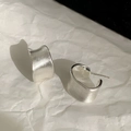 Vista detallada de pendientes minimalistas de plata con textura cepillada mate y diseño en C - Plateado