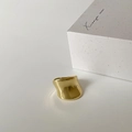 Detailed shot of a minimalist gold wide ring with irregular wave design on a white prop box - C-56 Gold Glossy (Wide Irregular Style)
