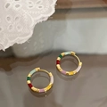 Detalle de pendientes de aro de esmalte de colores sobre un espejo vintage de lujo - Colorido