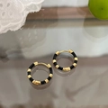 Detalle de aros franceses retro de oro y esmalte negro sobre encaje elegante - Negro