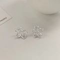 Close-up of minimalist hollow flower stud earrings in polished silver finish - Silver