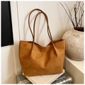 Detailed view of a brown suede tote bag placed on a suitcase in a minimalist setting - Brown
