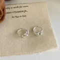Minimalist silver knot hoop earrings on beige linen cloth with a polished mirror finish - Silver