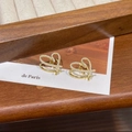 Macro detail of gold double heart earrings with crystal pavé on a rustic wooden table - Gold