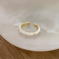 Detailed close-up of white enamel gold ring with tiny zircons on a ceramic tray - White Enamel (C-305)
