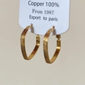 Dettaglio degli orecchini in rame dorato a forma di cuore e triangolo con finitura opaca - Oro Quadrato