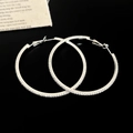Détail de grandes boucles d'oreilles créoles argentées avec pavé de zircon scintillant - Argent