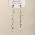 Detalle de pendientes largos con flecos de perlas, cadenas plateadas y perla de gota - Plateado