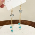 Detailansicht der goldfarbenen Schmetterlings-Ohrringe mit Opal-Perlen und Fransen - Blau