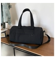 Detail of black nylon travel duffel bag with adjustable strap on a wooden table - Black