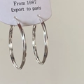 Close-up of silver hoop earrings with diamond-cut texture on a white jewelry tag - Diamond Cut Textured Large Hoop / Silver