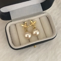 Detalle de pendientes de flores doradas con perlas en un estuche de joyería de lujo bicolor - Dorado / Perla Champán