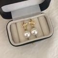 Detalle de pendientes de perlas con flores doradas sobre acolchado de joyero suave - Dorado/Perla Blanca