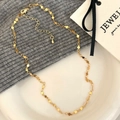 Primer plano de un collar de eslabones de corazón dorado sobre tejido y cerámica - Dorado