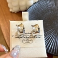 Dettaglio ravvicinato di orecchini a lobo a forma di C in argento su base bianca - Stile a Onda Larga a C / Argento