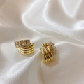 Detailed close-up of gold layered hoop earrings with rectangular cubic zirconia on white silk - Gold