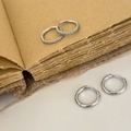 Detailed view of polished silver hoop earrings and zircon-studded huggie earrings on a book - Silver 4-Piece Hoop Earring Set
