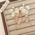 Détail de boucles d'oreilles à pompons de pétales, perles et chaînes dorées en boîte - Style de Gland de Quartz Rose