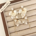 Gros plan de boucles d'oreilles à pompons fleurs et perles sur un présentoir en velours - Style de Gland de Perle Haute Brillance Blanc