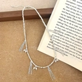 Dettaglio macro della collana con nappe d'argento e perle bianche su sfondo legno - Collana con nappa d'argento
