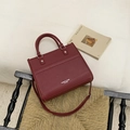 Detail van bordeauxrode leren tas met contrasterende stiksels op geweven stoel - Rood