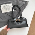 Glossy black underarm bag with gold buckle on a stylish minimalist background - Black