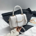 Bolso bandolera blanco de cuero trenzado con cierre dorado sobre fondo de chaqueta gris - Blanco