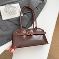 Dark brown leather shoulder bag with vintage gold buckle on a stylish suit and books - Brown
