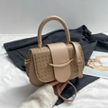 Beige saddle handbag with woven texture and gold metal buckle shown in lifestyle setting - Khaki