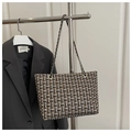 Detail der Tweed-Einkaufstasche mit Goldkette und Karomuster vor grauem Blazer - Schwarz