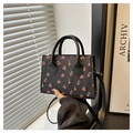 Close-up of black cherry print handbag with round handle and detachable shoulder strap - Black