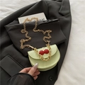 Sage green saddle bag with cherry detail and gold chain strap on black blazer - Green