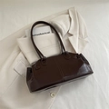 Dark brown glossy rectangular shoulder bag with fine straps on a beige blazer background - Brown