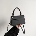 Minimalist black leather handbag with knotted handle detail and gold hardware accent - Black