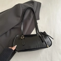 Minimalistische schwarze Halbmond-Schultertasche mit Metallbeschlägen auf grauem Blazer - Schwarz