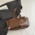 Bolso tote marrón con colgante M dorado y laterales de acordeón sobre traje gris - Marrón