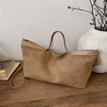 Grande borsa tote in pelle scamosciata kaki con tracolla regolabile su tavolo in legno - Cachi
