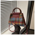 Detail of multi-color plaid tweed handbag featuring brown handle and red shoulder strap - Red