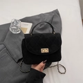 Quilted black suede handbag with gold lock and chain strap on a minimalist background - Black