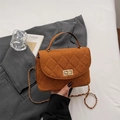 Brown quilted suede handbag with gold turn-lock and chain strap in a fashion setting - Brown