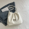 White faux leather pleated tote bag with a silver metal bow accent and dual straps - White